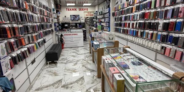A well-organized mobile phone accessory shop with cases displayed on walls and glass counters.