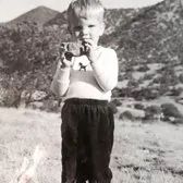 Ken as a child holding a rock like a camera
