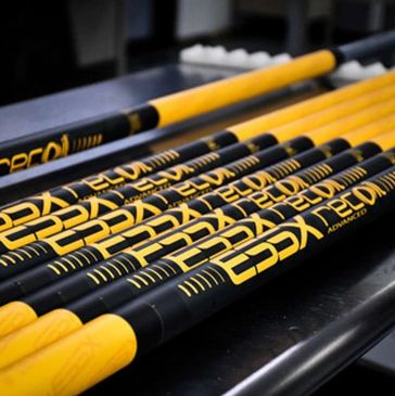 A set of yellow and black fishing rods aligned on a dark surface.