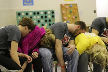 Four people sitting in chairs with their heads down, appearing to be asleep or resting.