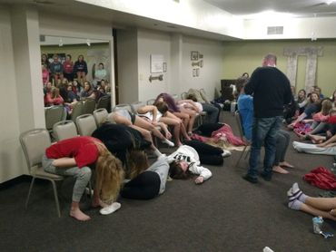 Group of young people participating in a hypnosis session indoors.