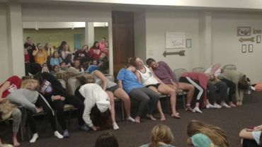 Group of people sitting and appearing to be hypnotized in a room.