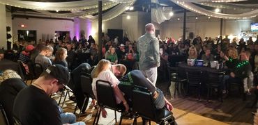 A performer entertains a crowd with a group of people appearing hypnotized on stage.