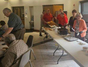 People gathered around a table with food in a community setting.