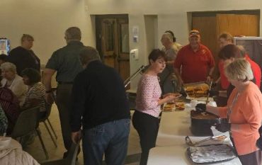 People serving and receiving food in a communal setting.