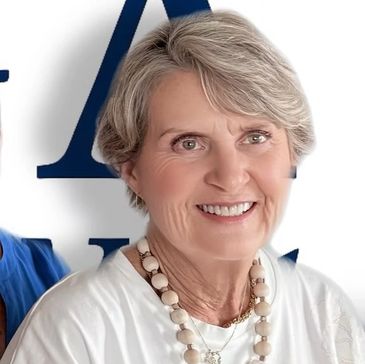 Smiling elderly woman with short silver hair and a beaded necklace.