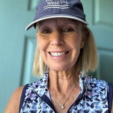 Smiling woman wearing a hat and butterfly-patterned sleeveless top.
