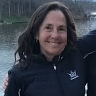 Woman smiling outdoors near water.