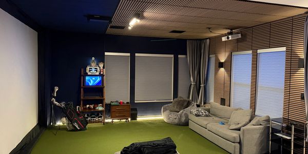 Cozy indoor golf simulation room with modern furniture and green turf.