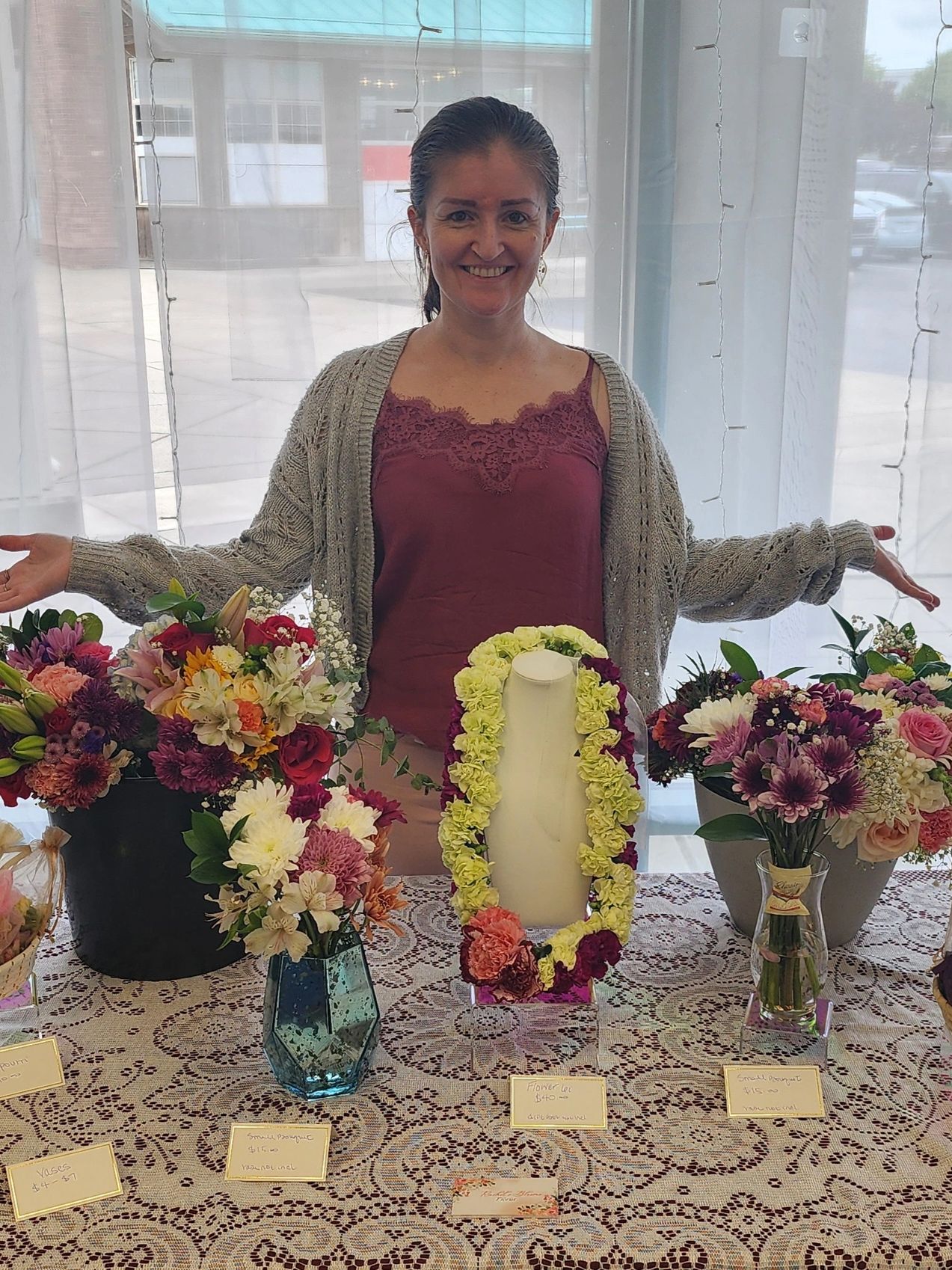 Woman smiling behind a table with flower bouquets.
