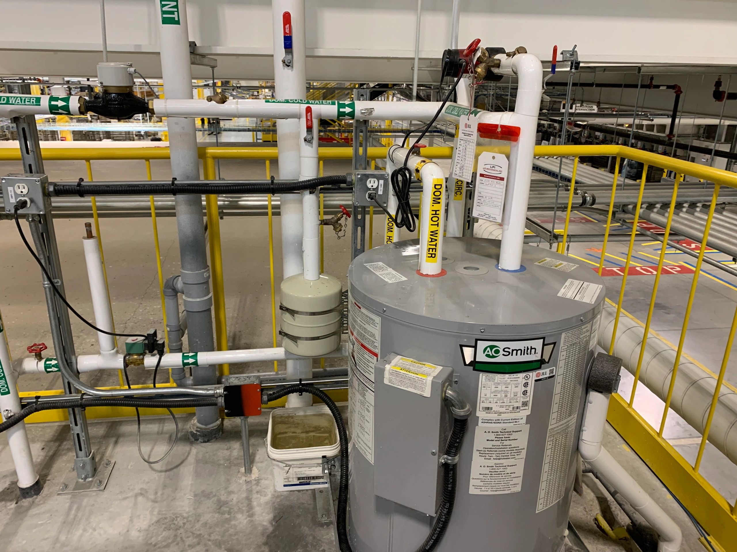 Industrial water heater system with labeled pipes for hot and cold water.