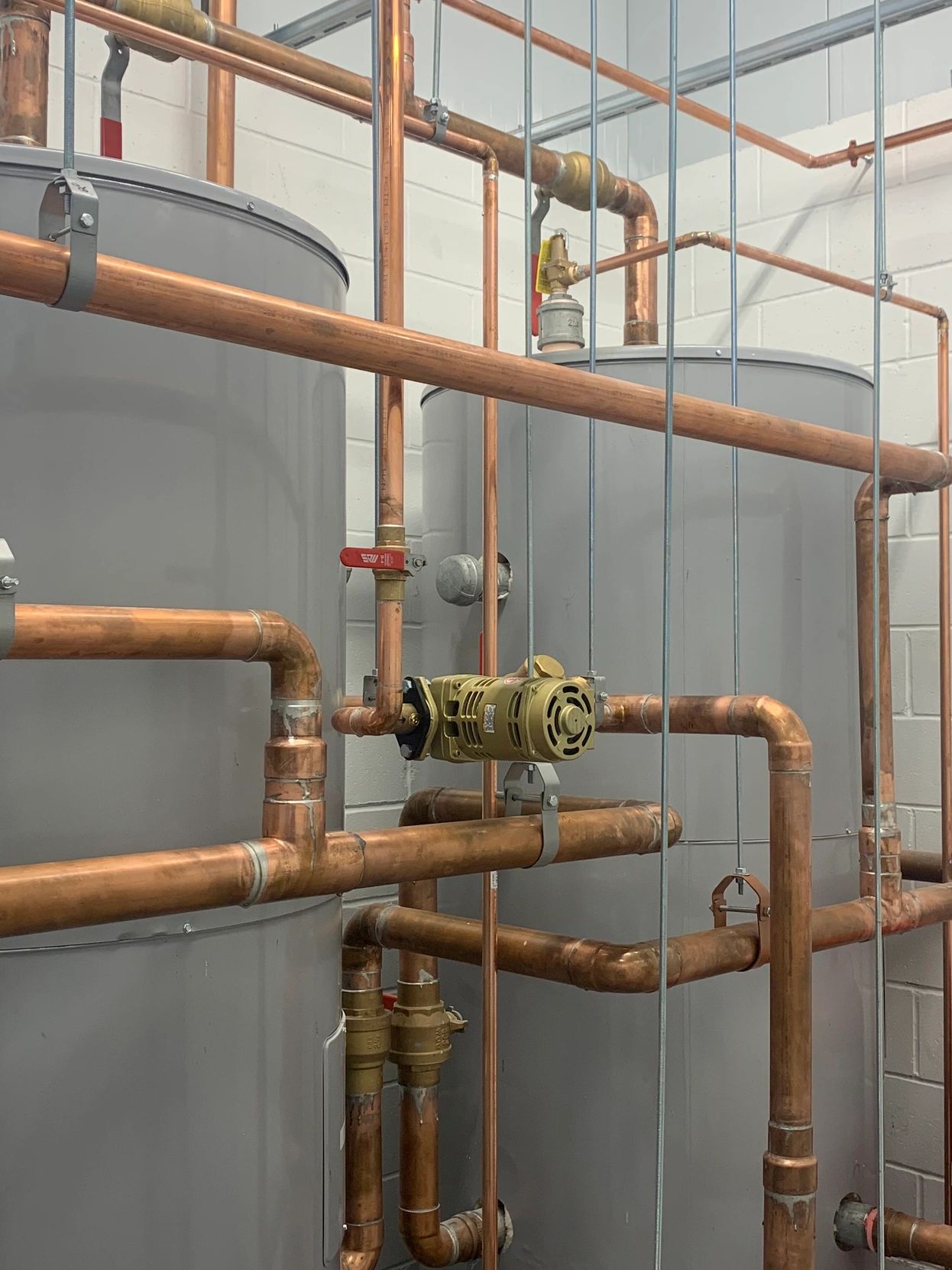 Industrial room with large gray tanks and copper piping system.