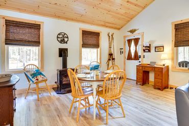 Charming cabin dining room featuring a wood table, wooden floors, and a glowing wood-burning stove.