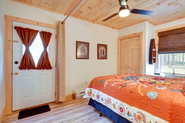Cozy bedroom with orange floral quilt, wood ceiling, and white door.
