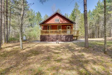 Rustic red cabin nestled in a wooded area.