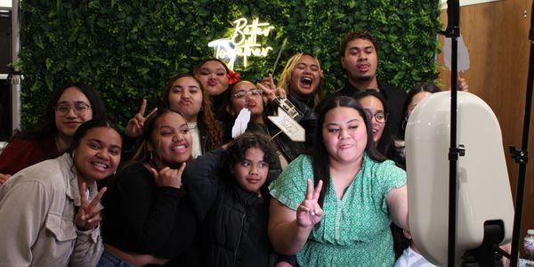 A group of friends posing happily for a photo in front of a green backdrop with a neon sign.