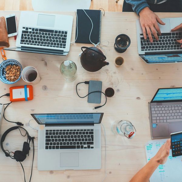 Top view of a collaborative workspace with laptops and notebooks.