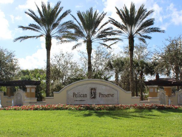 Entrance sign for Pelican Preserve with palm trees and greenery.