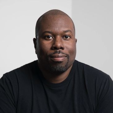 Portrait of a man with a neutral expression wearing a black shirt.