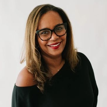 Smiling woman with glasses and shoulder exposed.