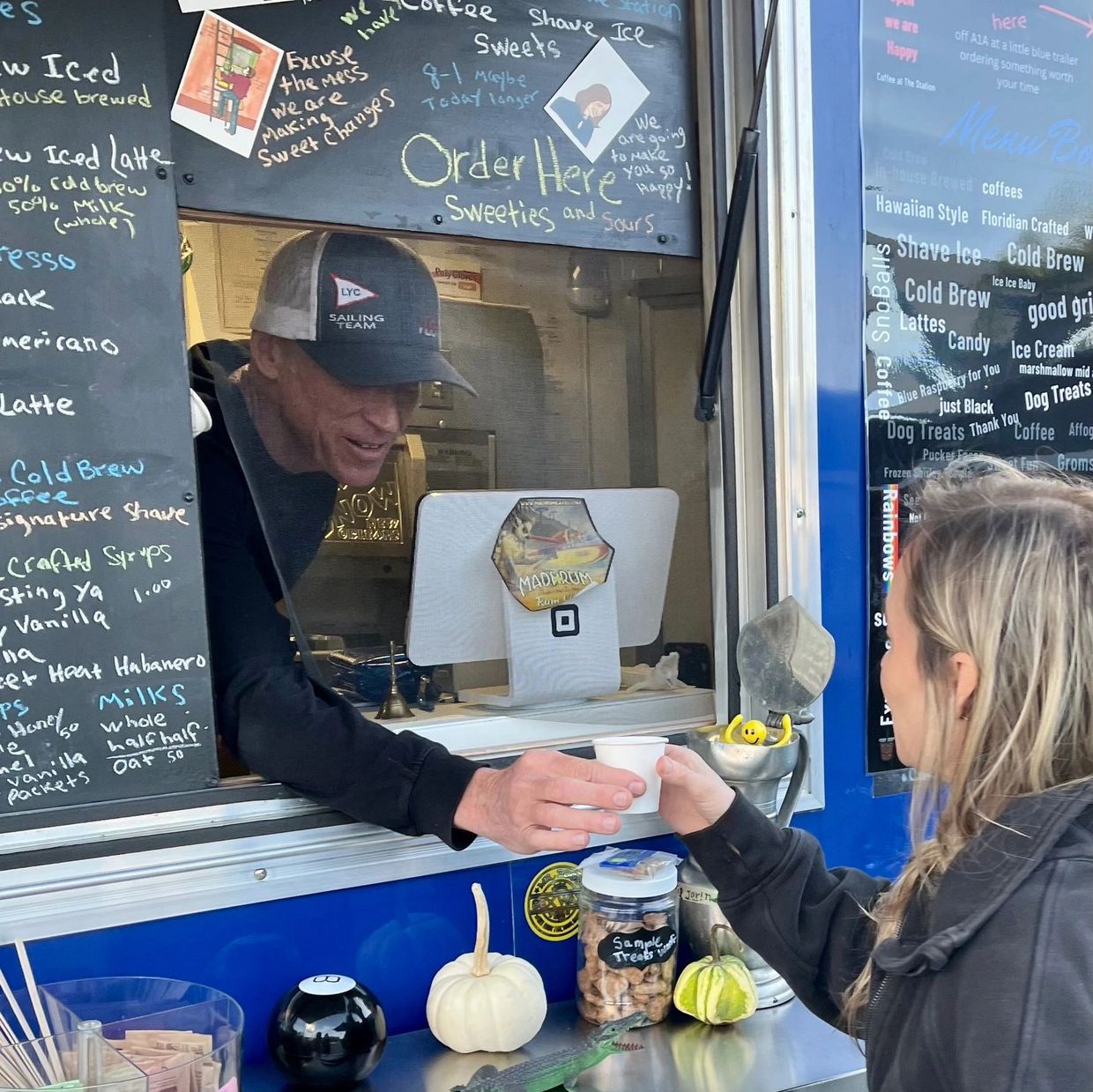 a girl recieving an espresso coffee from the barista at a coffee trailer