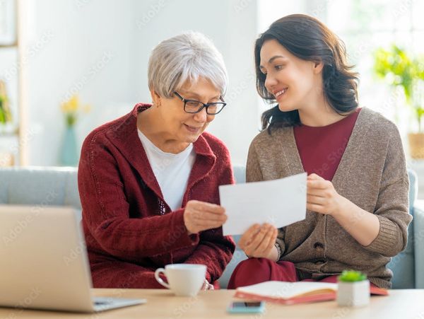 Two women happily looking at a document together at home.