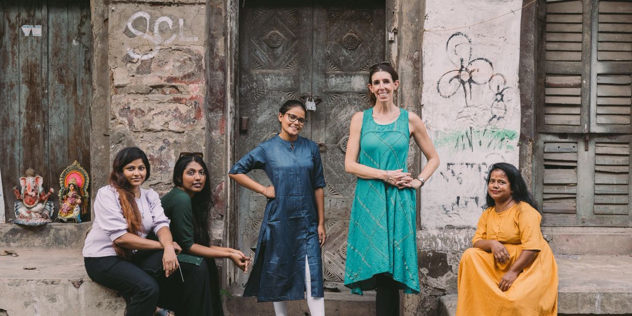 Group of five women posing in front of an old building.