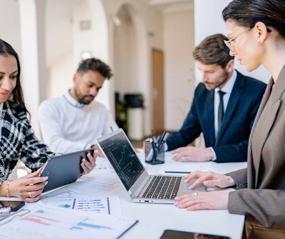 Four professionals analyzing data and charts in a meeting room.