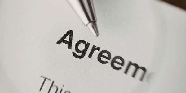 Close-up of a pen pointing at the word 'Agreement' on a document.