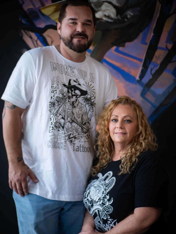 A man and woman posing indoors with artistic wall backdrop.