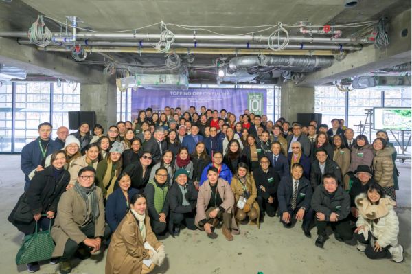 Large group posing at a construction site during topping off event.
