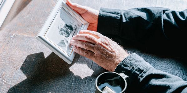 Person holding a framed photo while drinking tea.