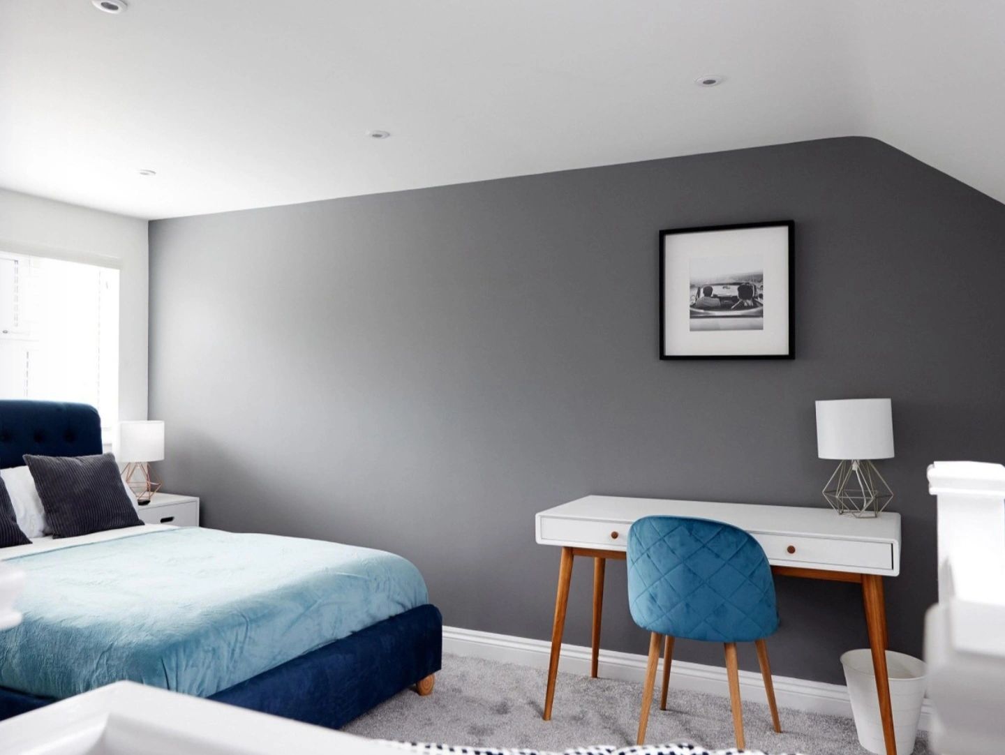 Minimalist bedroom with blue accents and white furniture.