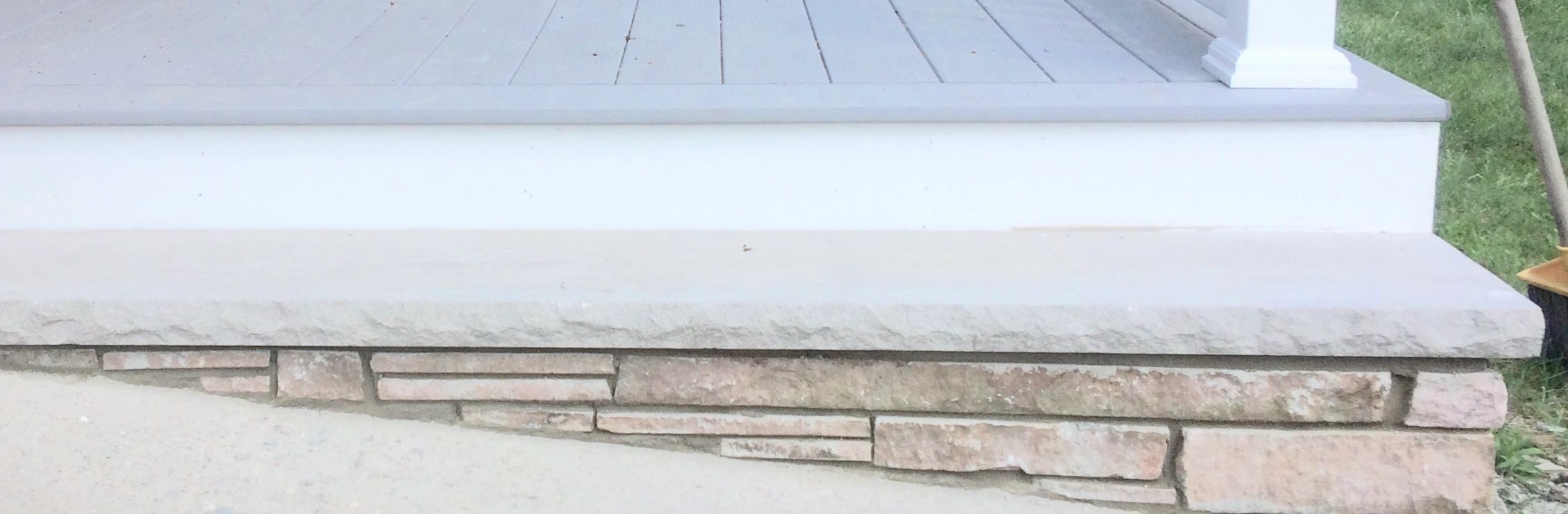 Stone step with layered stone facade and gray wooden porch.