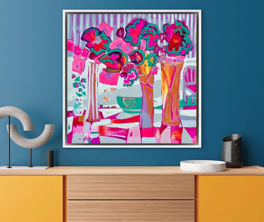 Colorful abstract floral painting on a blue wall above a modern cabinet.