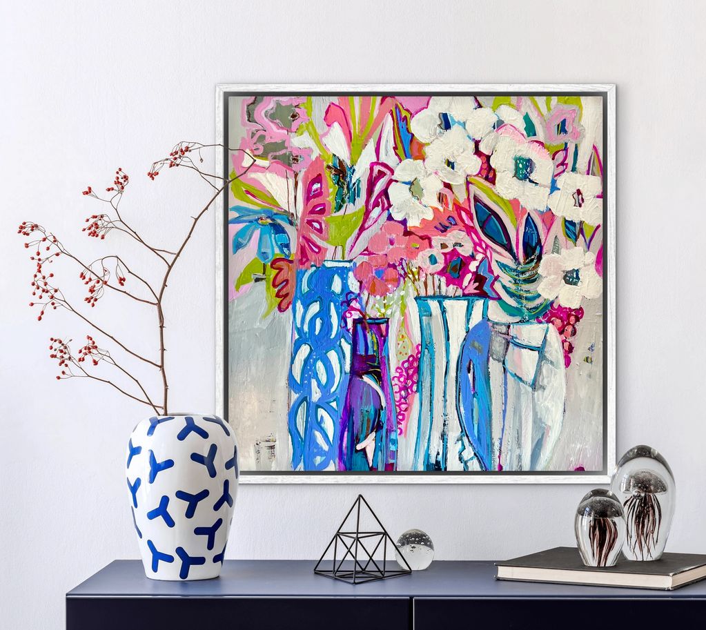 Colorful abstract floral painting above a modern console with decorative objects.