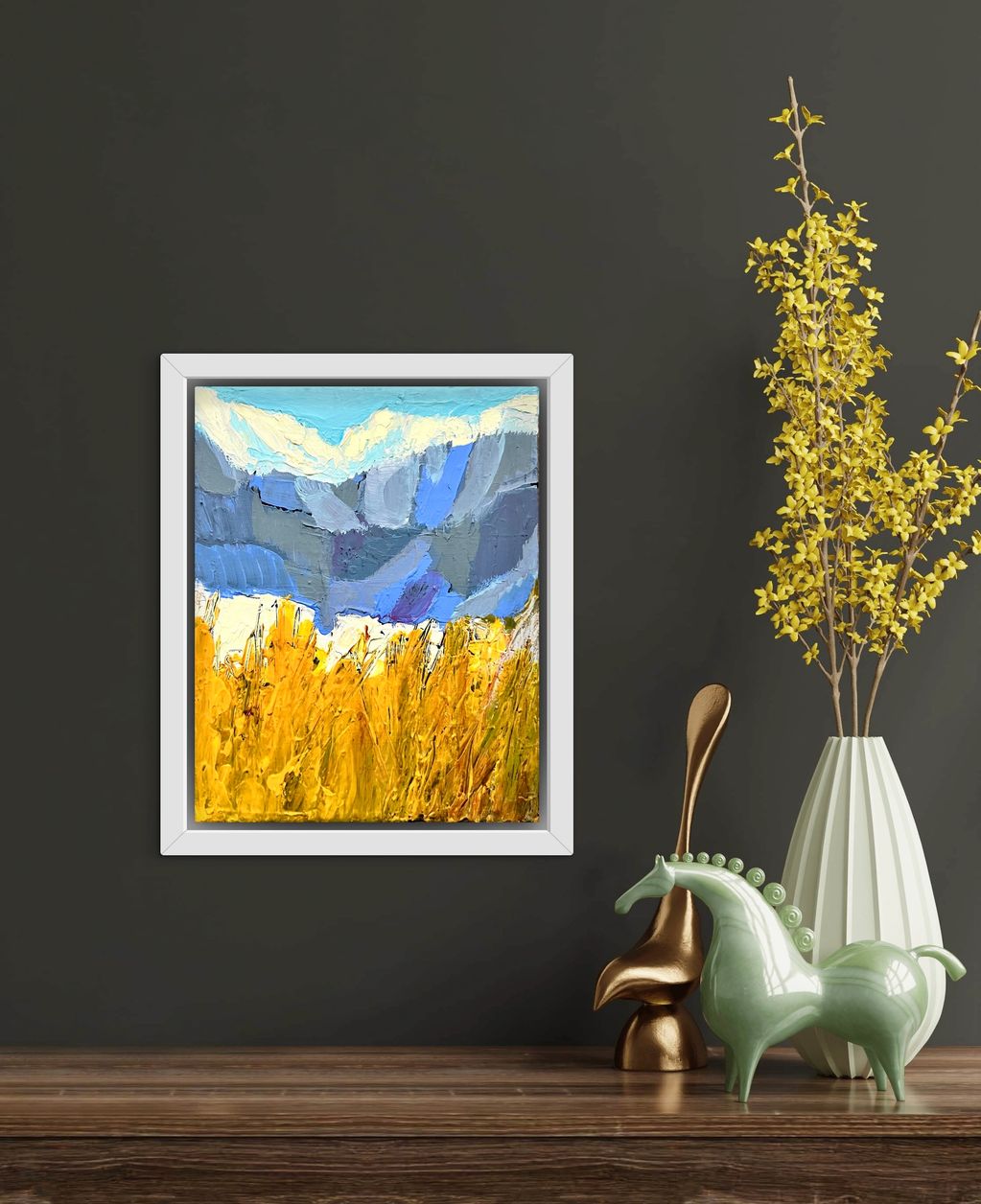 Abstract mountain landscape painting with yellow fields in a white frame.
