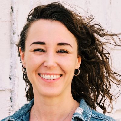 Smiling woman with wavy hair wearing a denim jacket.