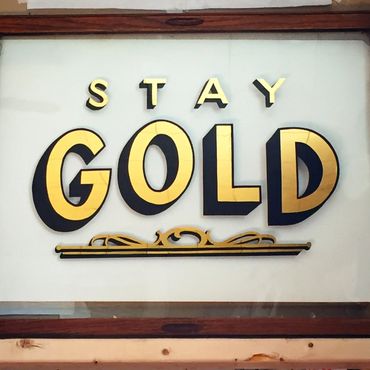 Glass gilding with gold leaf that says "Stay Gold."