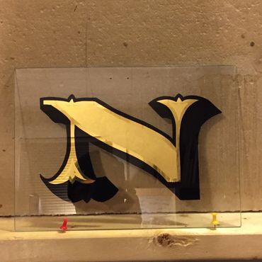 Gold leaf letter N on glass.