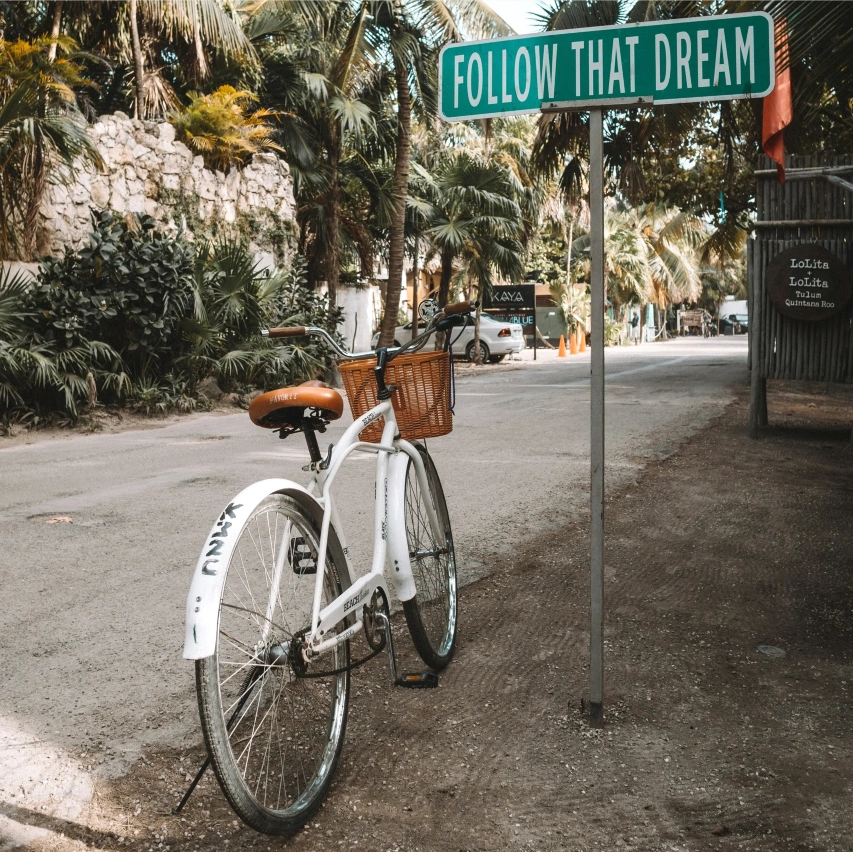 A bicycle with a sign that says "FOLLOW THAT DREAM"