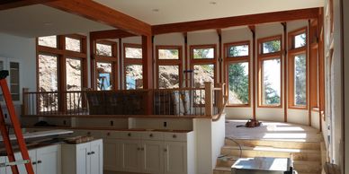Bright room under construction with large windows and wooden frames.