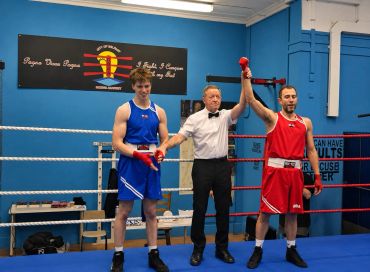 Boxer in red wins a match in the ring.