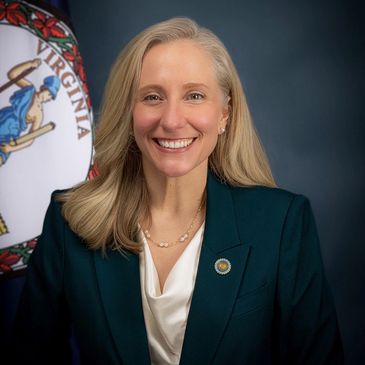 Professional woman smiling in front of Virginia state flag.