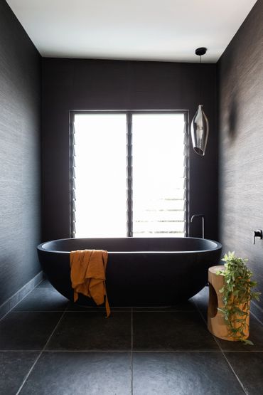 Matte black free standing bath with matte black spout and mixer.