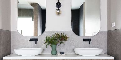 Twin bathroom vanities with matte black basin mixers.