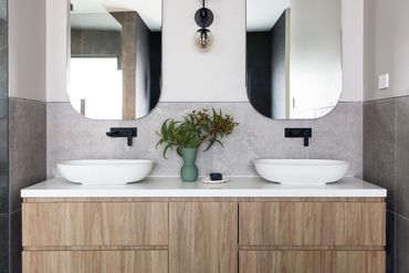 Twin bathroom vanities with matte black basin mixers.