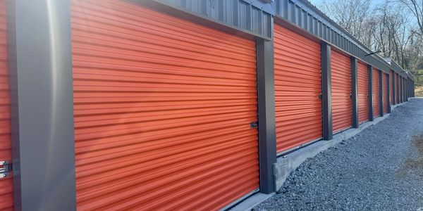 Row of orange storage unit doors under a metal roof.