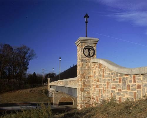 Stone bridge with a decorative lamp post and symbol.