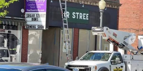 Store sign announcing 'Sugar Street Buns' coming soon.